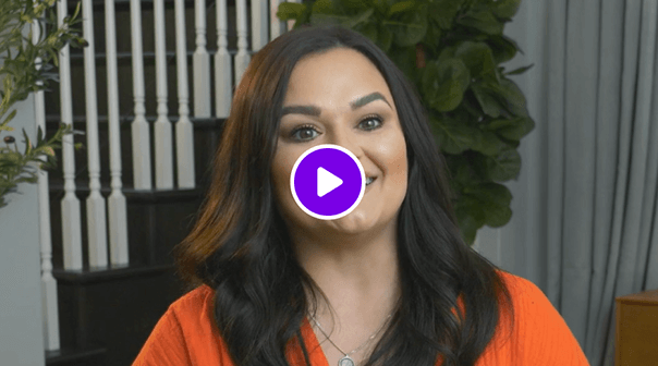 Video thumbnail of a smiling woman wearing an orange top, with stairs and plants in the background.