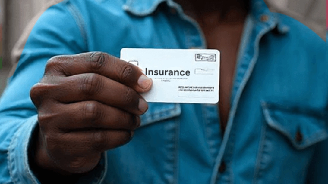 A person wearing a blue shirt holding an insurance card in his right hand.